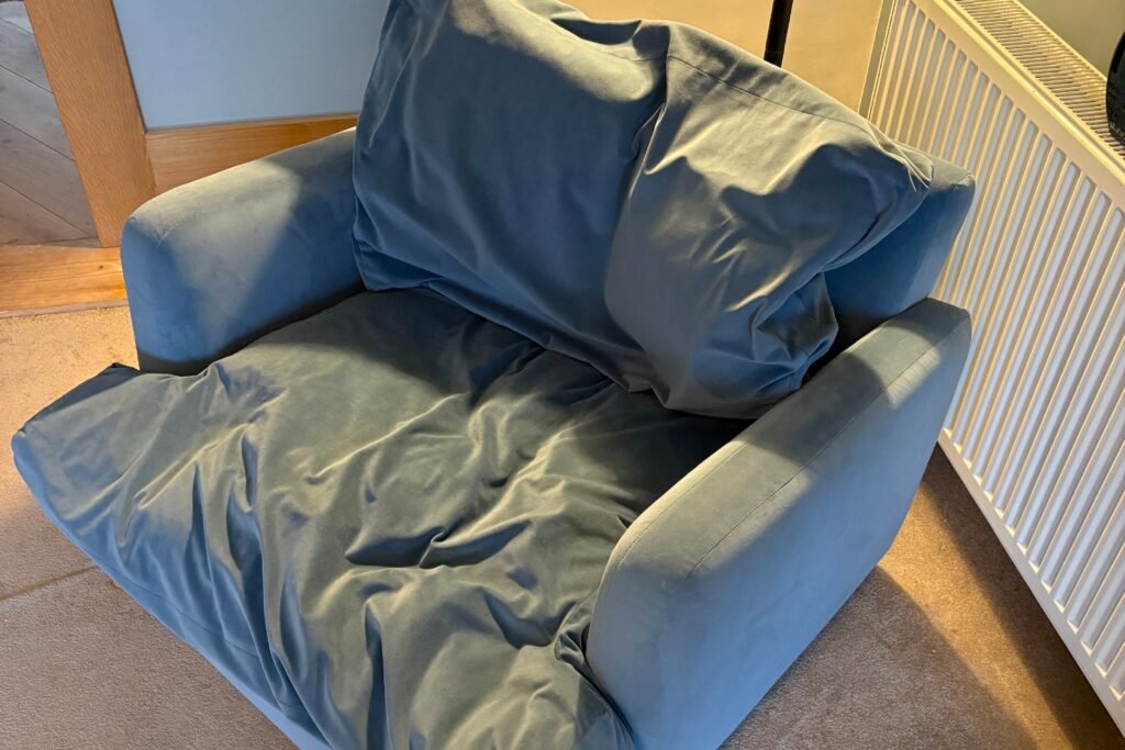 Blue chair in Ashby‑de‑la‑Zouch showing collapsed, uneven cushions before refilling