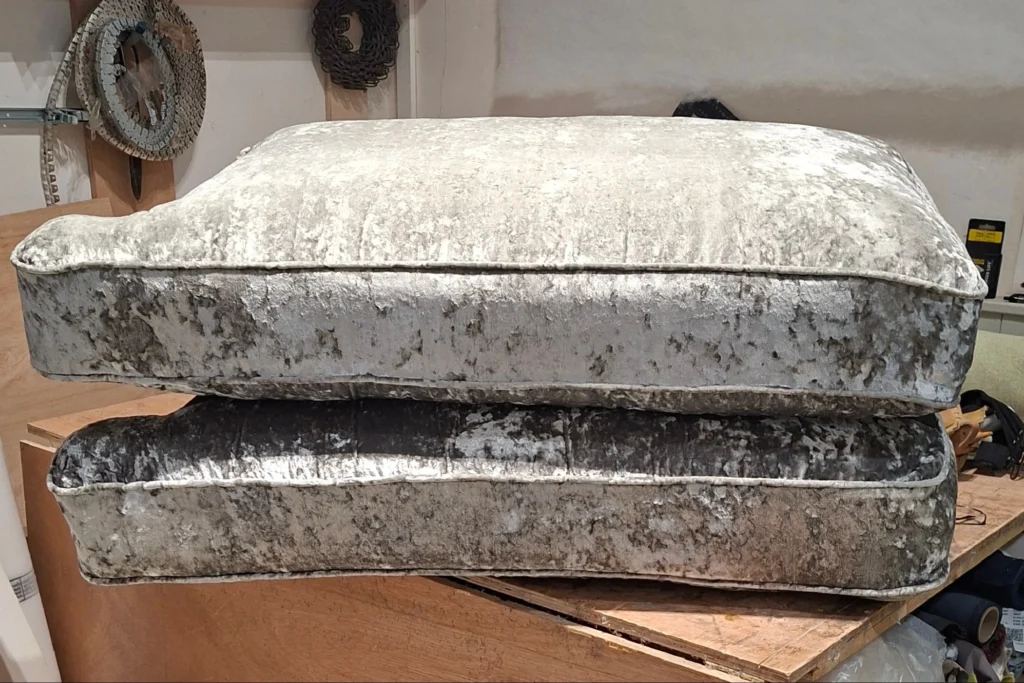A three seater sofa cushions on the workshop cutting table with new cushion interiors inserted. Looking very plump.